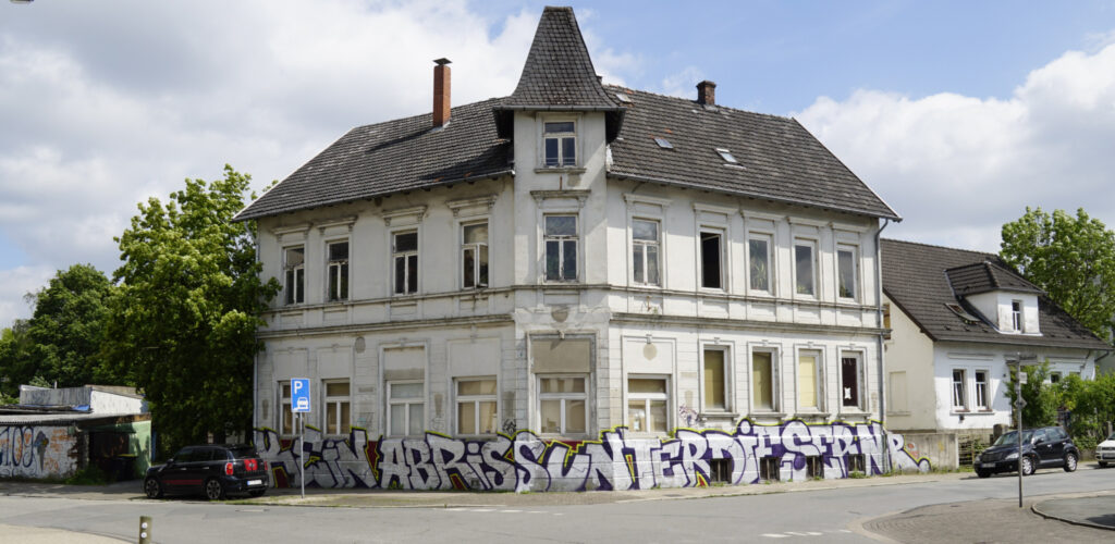 Ein Bild des Hauses Petristraße 2. Unten ist ein Graffito angebracht, das "Kein Abriss unter dieser Nr." aussagt.

Leichte Sprache:
Auf dem Bild ist das Haus Petristraße 2.
Unten ist ein Satz aufgemalt.
Der Satz lautet:
"Kein Abriss unter dieser Nr."